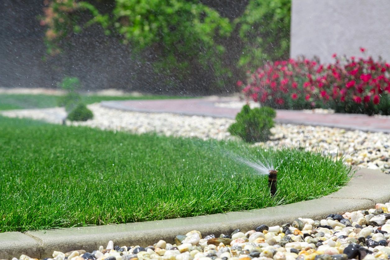 Garden sprinkler on grass with flowers